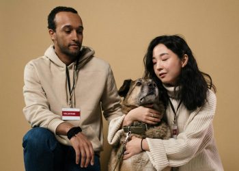 A caring couple of volunteers with a rescue dog in a studio setting.